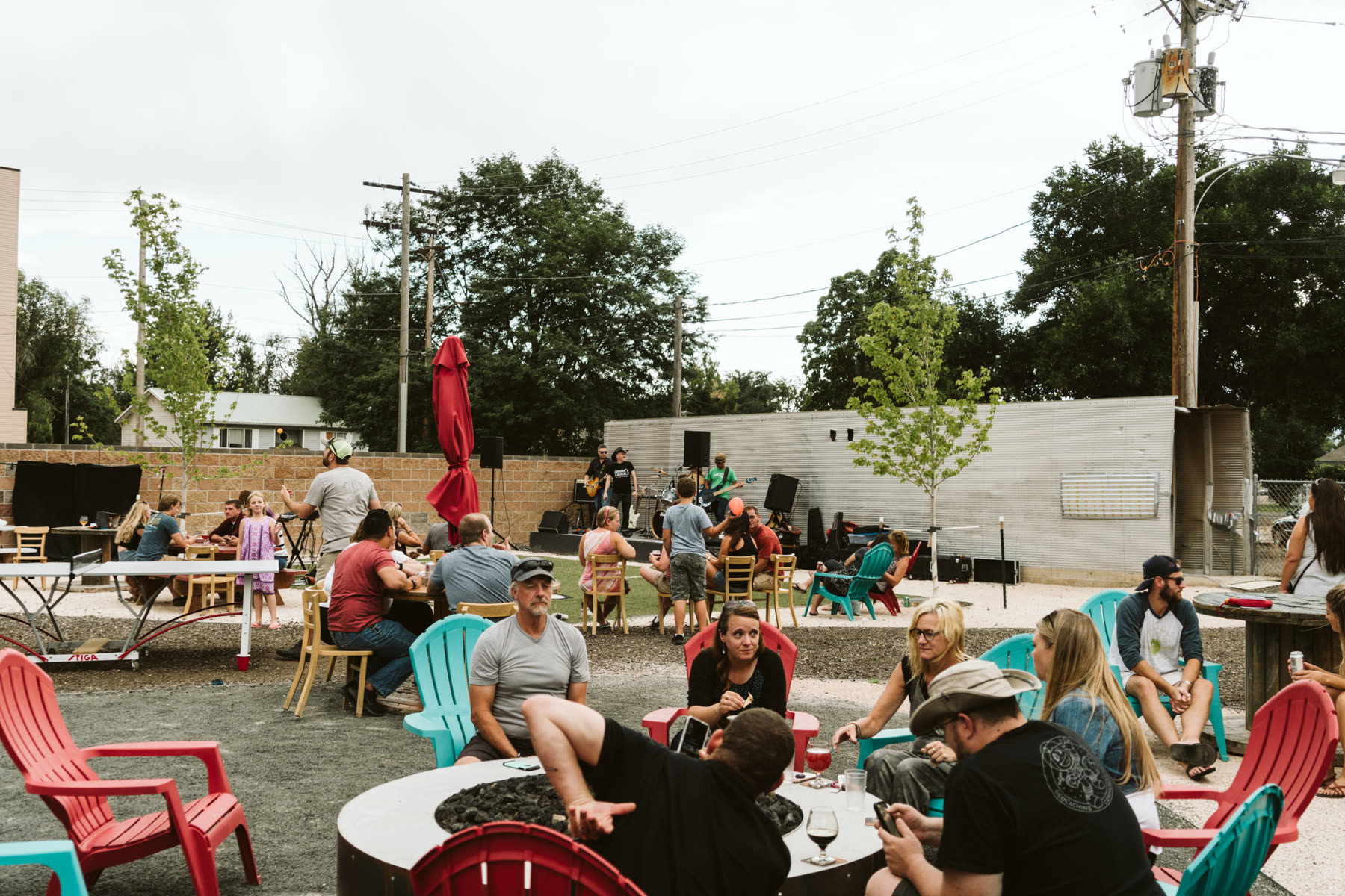 The Backyard Tap yard on a sunny afternoon — red and teal Adirondack chairs around the fire pits